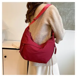 Détail du sac demi-lune en nylon bordeaux avec large sangle et tirettes de zip tressées