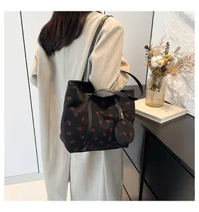 Close-up of black corduroy tote bag with red strawberry embroidery and matching mini coin pouch