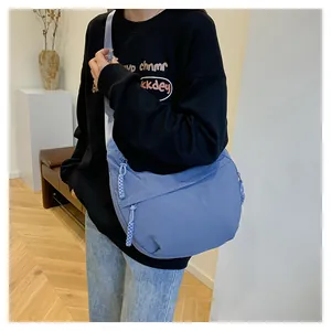 Détail du sac demi-lune en nylon bleu avec tirette violette tissée et texture de tissu mat