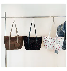 Three corduroy strawberry tote bags with matching small pouches on metal hangers