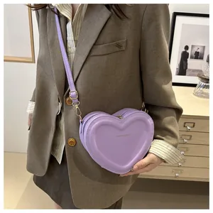 Detail showing the lavender heart-shaped crossbody bag with embossed lettering on PU leather