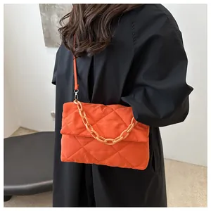 Détail du sac matelassé orange avec chaîne acrylique et bandoulière porté par un modèle