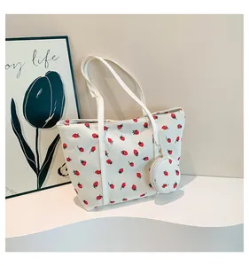 Detail view of cream corduroy tote bag with red strawberry pattern and small round pouch