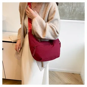 Détail du sac hobo en nylon bordeaux avec bandoulière large et cordon de zip tressé