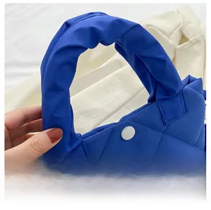 Detail der blauen gesteppten Beuteltasche mit gedrehtem Griff und Magnetverschluss