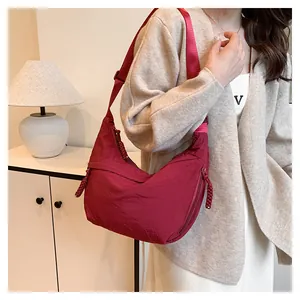 Détail du sac hobo croissant en nylon bordeaux avec bandoulière réglable et nœud zip