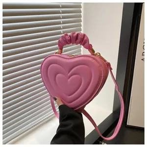 Détail du sac à main rose en forme de cœur avec texture gaufrée et poignée plissée