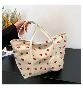 Detailed texture of beige corduroy tote bag with red strawberry prints and small pouch