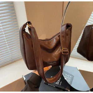 Détail du sac bandoulière marron foncé montrant le cuir texturé et l'étiquette mode