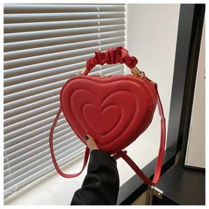 Détail du sac rouge en forme de cœur avec coutures concentriques et anse plissée