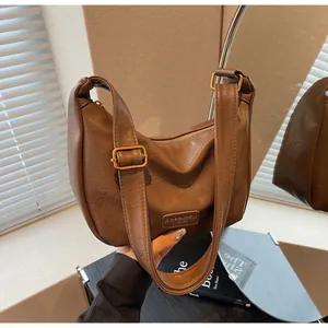 Détail d'un sac Hobo marron avec texture cuir vintage et boucle en métal doré chic