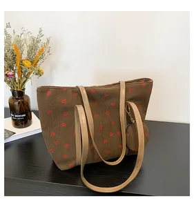 Detail of brown corduroy tote bag featuring red strawberry patterns and a small round coin purse