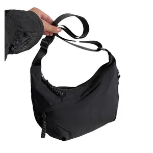Sac bandoulière demi-lune minimaliste en nylon noir avec bandoulière et zips tressés