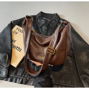 Détail de la texture du sac dumpling marron foncé avec boucle dorée et bandoulière