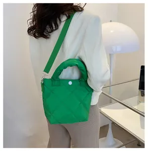 Detail einer grünen Stepptasche mit gepolstertem Griff und weißem Druckknopfverschluss