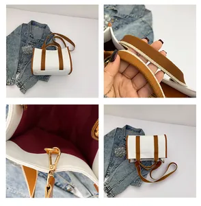 Detail view of white canvas tote bag with brown straps and red lining showing metal buckles
