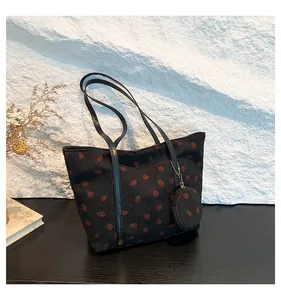 Detail of black corduroy tote bag with red strawberry pattern and mini coin purse charm