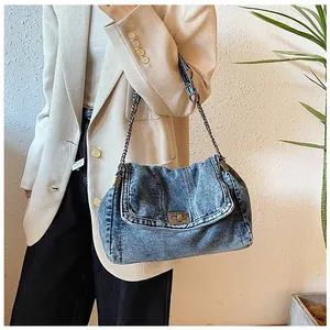 Detail of washed blue denim bag featuring silver metal twist lock and chain strap