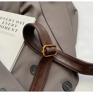 Détail de la bandoulière en cuir marron foncé avec boucle dorée et coutures de précision