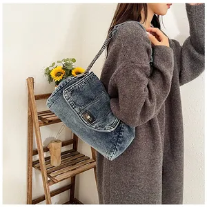 Detail of blue denim canvas shoulder bag with silver chain strap and metal swivel lock