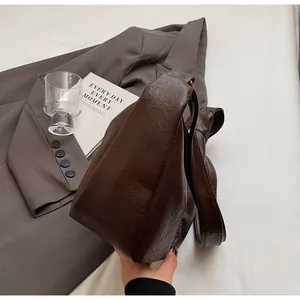 Détail de la texture en cuir souple et de l'espace intérieur de ce sac à bandoulière marron