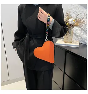 Detail of a heart-shaped orange leather coin purse with a colorful LOVE lanyard