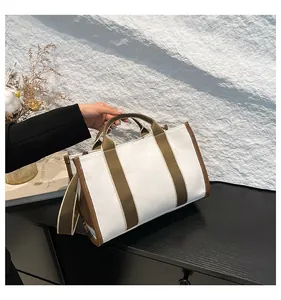 Detalle del bolso tote de lona con asas de cuero marrón y correa ajustable al hombro