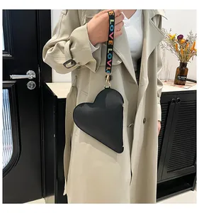 Detail of a black heart-shaped bag with a colorful LOVE rainbow strap and gold metal hardware