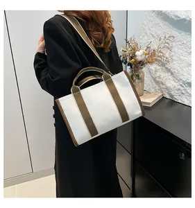 Canvas tote bag with brown trim shown worn crossbody for a stylish daily commute look