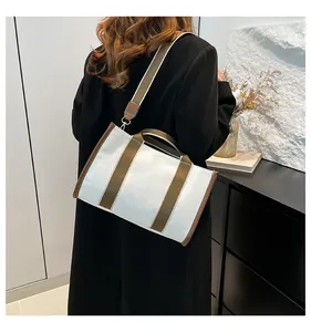 Modern canvas tote bag shown from a back view with brown straps in a minimalist home setting