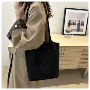 Borsa a spalla minimalista in camoscio nero con trench beige in un ambiente raffinato
