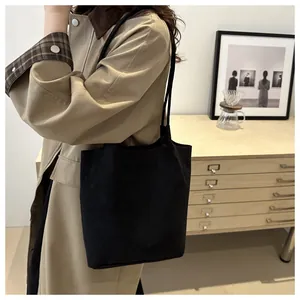 Minimalist black suede tote bag detail shown with a long khaki trench coat for autumn