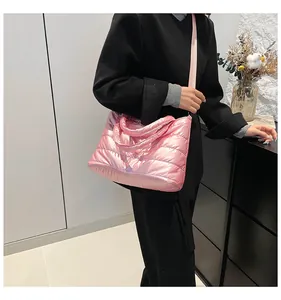 Gros plan du sac matelassé rose avec fini brillant et large bandoulière en textile