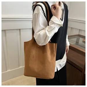 Dettaglio di una borsa a secchiello in camoscio marrone indossata da una modella
