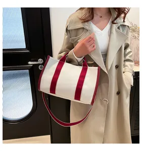 Minimalist canvas tote with burgundy red straps shown in a chic outdoor fashion styling
