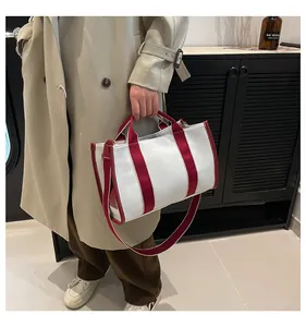 Detail of canvas tote bag with burgundy straps and shoulder strap for daily commute