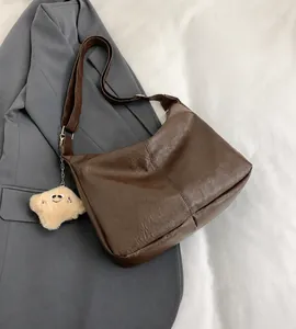 Detail view of coffee leather tote with plush charm and vertical stitching detail