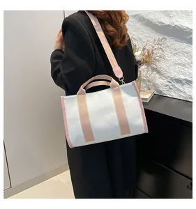 Detailed view of white canvas tote bag with pink straps worn by model for size reference