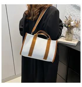 Modern white canvas tote bag with brown straps shown on a model in a minimalist setting