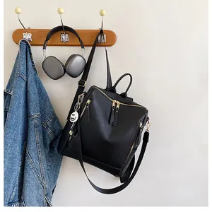 Detailansicht des schwarzen Rucksacks aus Leder mit Gold-Zippern und Smiley-Anhänger