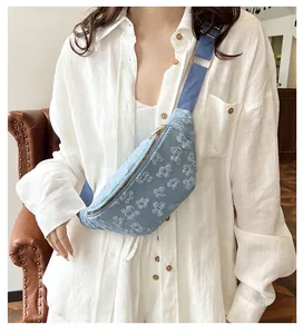Detail of light blue crossbody chest bag featuring embossed floral texture on a white shirt