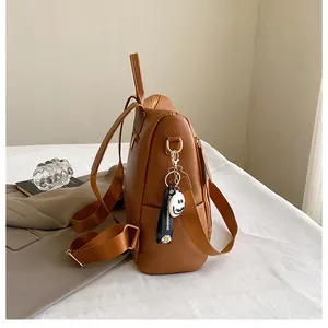 Seitenansicht des braunen Lederrucksacks mit Blumenanhänger und strukturiertem Gurt