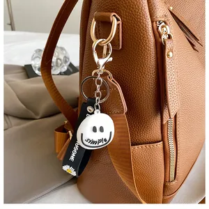 Detail eines Silikon-Schlüsselanhängers mit Gänseblümchen an einem braunen Lederrucksack