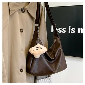 Detail of large brown hobo bag with pebble leather texture and plush cloud charm