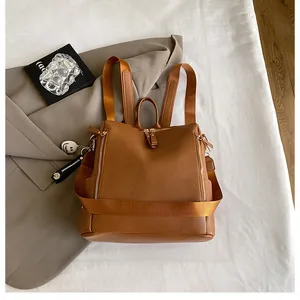 Detailansicht des karamellfarbenen Lederrucksacks mit Doppelreißverschluss und Blumenanhänger