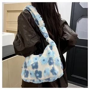 Detail of white plush hobo bag featuring blue floral textures and soft shoulder strap