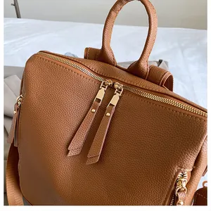 Detailaufnahme des braunen Lederrucksacks mit Litschi-Muster und Gold-Reißverschlüssen