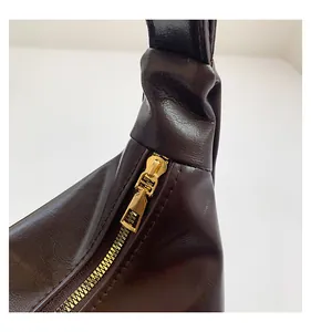 Detail of dark brown faux leather tote with textured finish and premium gold zipper hardware