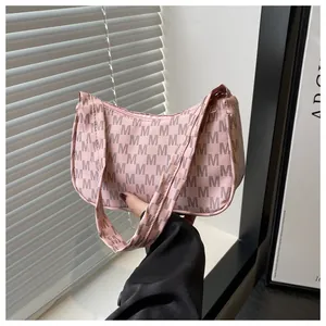 Close-up of pink monogram crescent bag with all-over M-letter print and top zipper