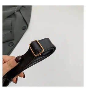 Detail of adjustable deep brown leather shoulder strap with elegant gold metal buckle